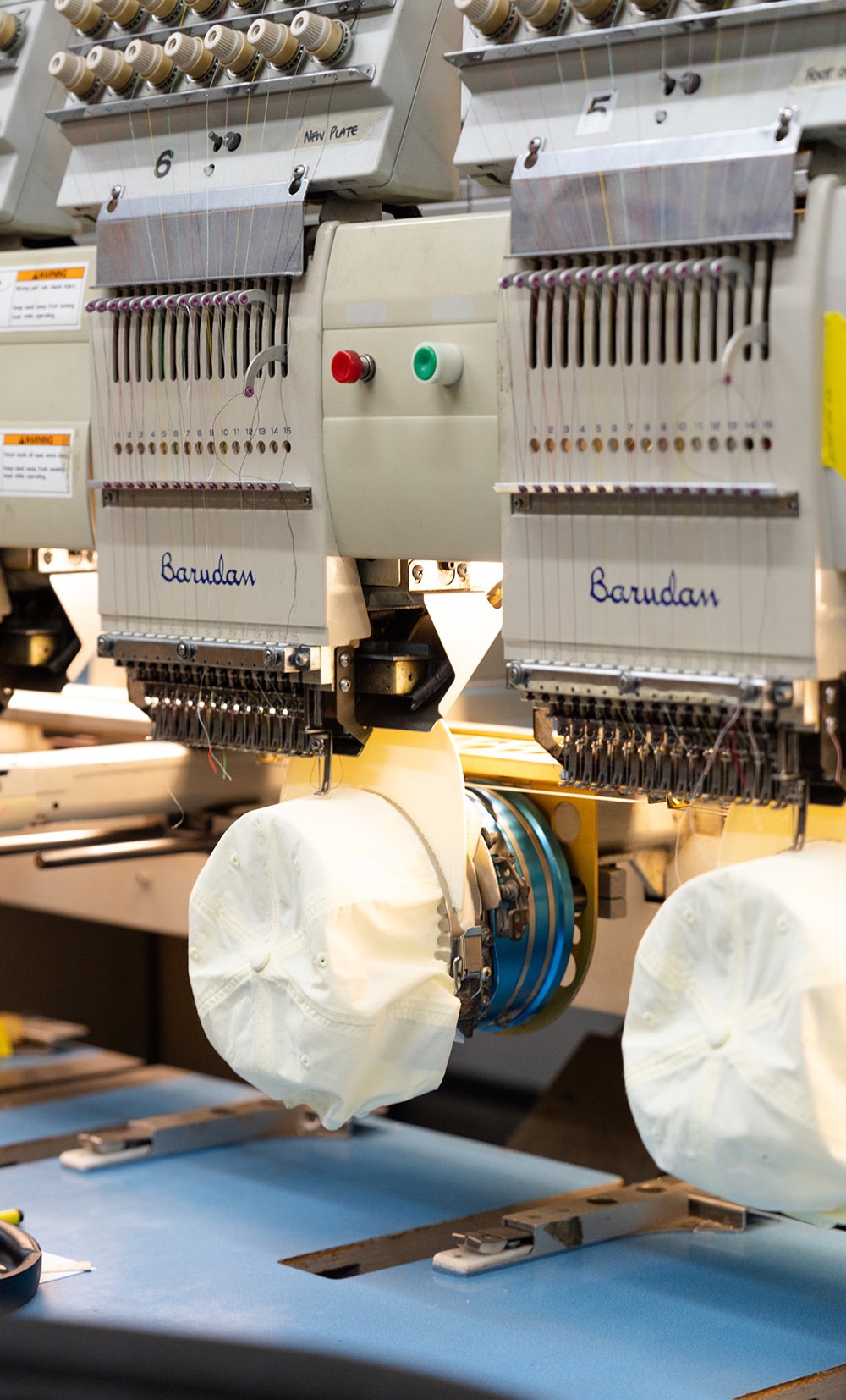 Commercial embroidery machines stitching white caps